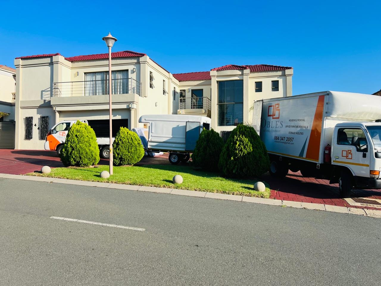 Obles Removals trucks parked outside a large home during a residential move