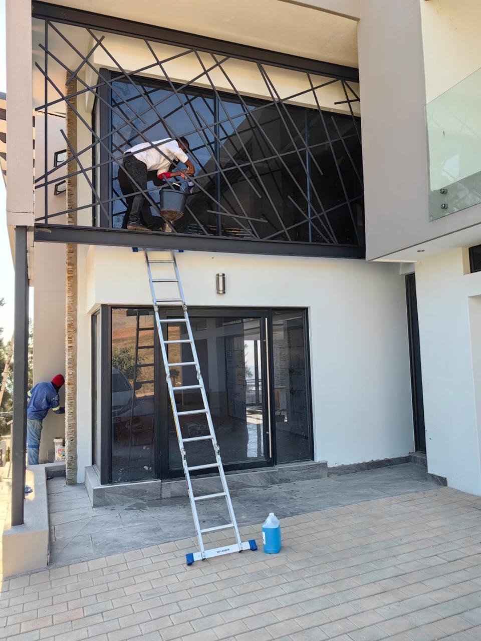 Cleaner working from a ladder on an exterior balcony window