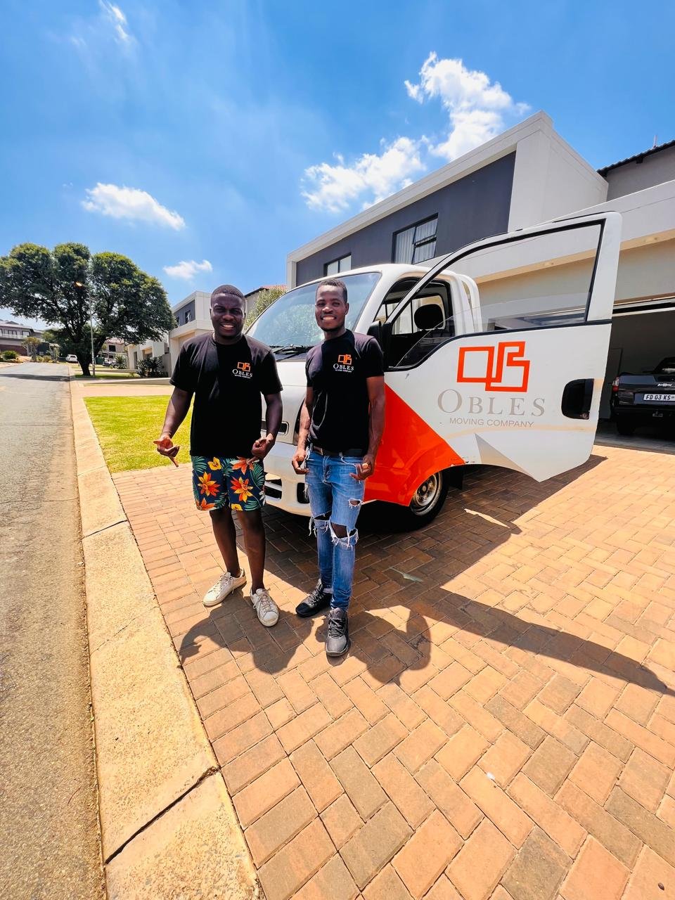Two Obles Removals team members standing beside a branded moving truck